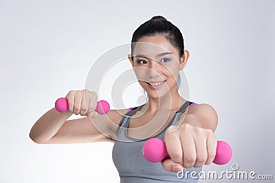 Young asian sporting woman training with dumbbell. Pretty athletic girl making physical exercise against white background. Health Stock Photo