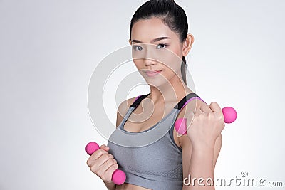 Young asian sporting woman training with dumbbell. Pretty athletic girl making physical exercise against white background. Health Stock Photo