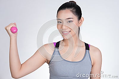 Young asian sporting woman training with dumbbell. Pretty athletic girl making physical exercise against white background. Health Stock Photo