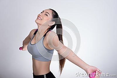 Young asian sporting woman training with dumbbell. Pretty athletic girl making physical exercise against white background. Health Stock Photo