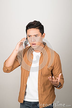 Young Asian student taking on cell phone and feeling surprised Stock Photo