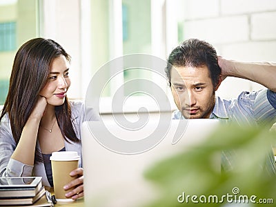 Young asian teammates working together in office using laptop co Stock Photo