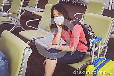 Young Asian tourist woman with mask sitting with distance at the airport Stock Photo