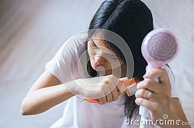 Young asian woman after bath hairbrushing her hair with comb,Female drying her long hair with dryer Stock Photo