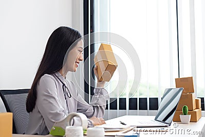 Young Asian woman chatting with a customer on a laptop and displays the product before delivery to confirm the order Stock Photo