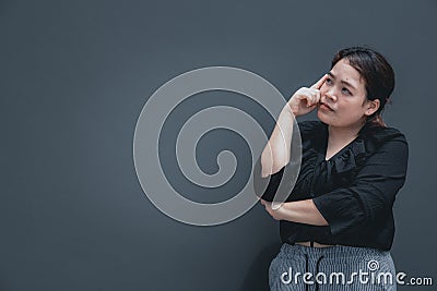 Young asian woman with chubby body put her finger on face looking away to think about something. Stock Photo