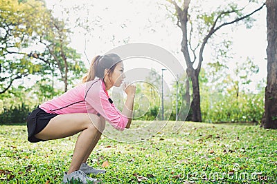 Young asian woman do squats for exercise to build up her beauty body in park environ with green trees. Stock Photo