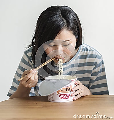 A young asian woman eating an instant noodles Stock Photo