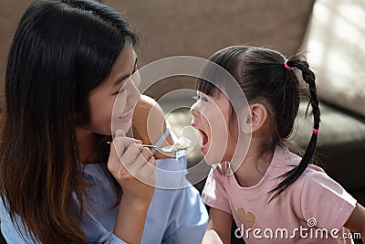 Young Asian woman feeding her younger sister with spoon of tasty cake Stock Photo