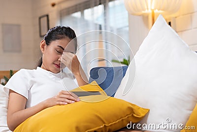 Young asian woman feeling stress and closed eyes suffering from headache and lying down on sofa in living room,tired female of Stock Photo