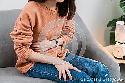 Young Asian woman hands holding the stomach and pain period cramps because having menstruation. Stock Photo