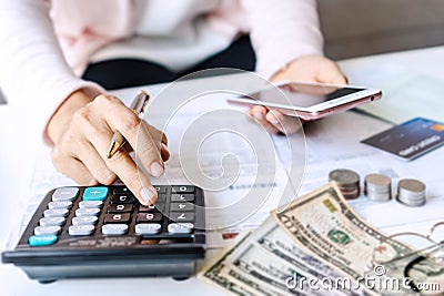 Young Asian woman holding smart phone while using calculator for business financial accounting calculate money bank loan rent Stock Photo