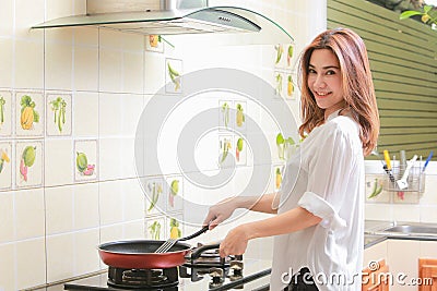 Young asian woman making omelette in a kitchen. Stock Photo