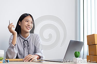 Young Asian woman is an online merchandiser and is currently managing conversations and receiving orders from customers via the In Stock Photo