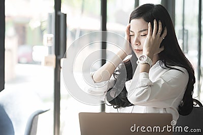 young asian woman put hand on head feeling tired at office. businesswoman frustrate and stress from hard work while sitting Stock Photo