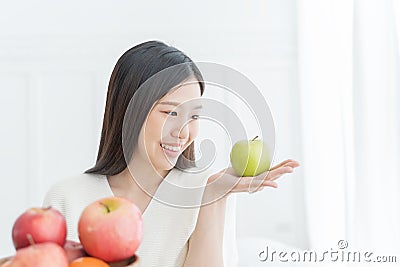 Young Asian woman showing green apple and red apple, indoors portrait. Stock Photo