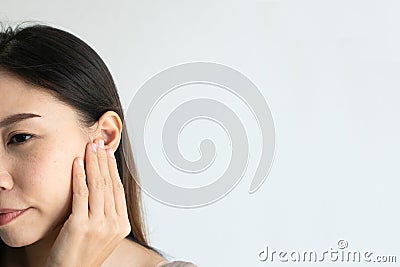 Young Asian woman with sore ear suffering from otitis over white background. Girl touch her ear with pain. Ear problem Stock Photo