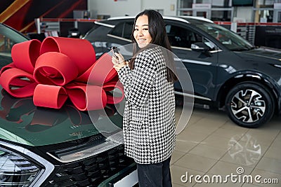 Young asian woman stands in front car with gift bow Stock Photo