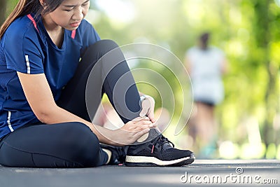 Young asian woman suffering ankle injury. Runner girl is injured by sprain ankle while running or exercising. Female runner Stock Photo