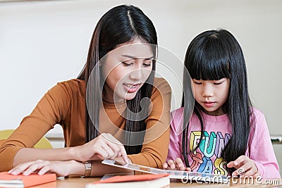 Young asian woman teacher teaching girl in kindergarten classroom, preschool education concept Stock Photo