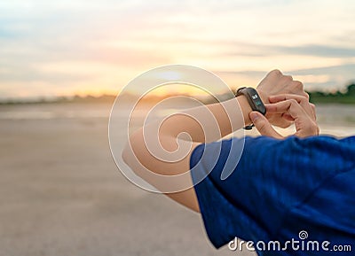 Young Asian woman touching smart band after running in the morning. Wearable computer. Heart rate monitor bracelet. Fitness device Stock Photo