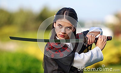 Young asian woman in traditional kimono trains in a fighting stance close-up portrait with katana sword samurai warrior girl in Stock Photo