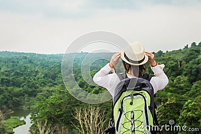 young asian woman traveler with backpack relaxing on mountian and looking forest Stock Photo