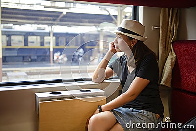 Young asian woman traveling looking out the window while sitting in the train Stock Photo