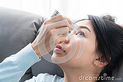 Young Asian woman uses eye drops for eye treatment. Redness, dry eyes, allergy and eye itching. Vision and ophthalmology medicine Stock Photo