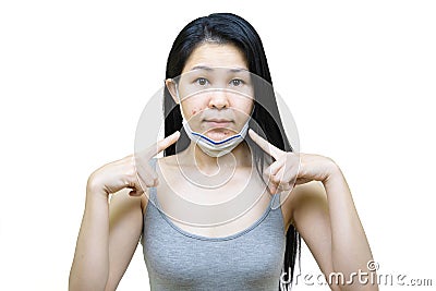 Young asian woman wearing medical face mask her hand point at pimple on chin,Skin allergy,acne from wearing a mask Stock Photo