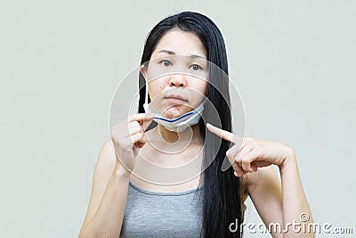 Young asian woman wearing medical face mask her hand point at pimple on chin,Skin allergy,acne from wearing a mask Stock Photo