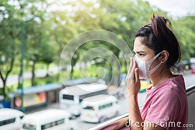 Young Asian woman wearing N95 respiratory mask protect and filter pm2.5 particulate matter against traffic and dust city. Stock Photo