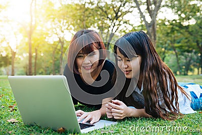 Happy hipster young asian women working on laptop in park. Student studying outdoors. Stock Photo