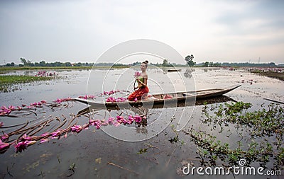 Young Asian women in Traditional dress in the boat and pink lotus flowers in the pond. Stock Photo