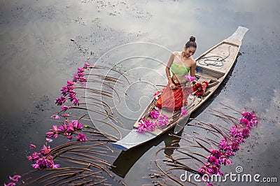 Young Asian women in Traditional dress in the boat and pink lotus flowers in the pond. Stock Photo