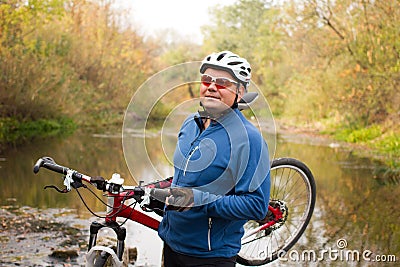 Young athlete crossing rocky terrain with bicycle in his hands Stock Photo