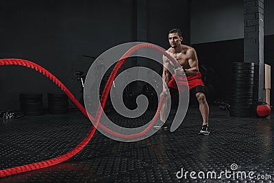 Young athlete doing battle ropes exercise at the crossfit gym Stock Photo