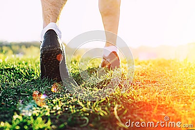 Young athlete feet running in park closeup on shoe. Male fitness athlete jogger workout in wellness concept at sunset Stock Photo