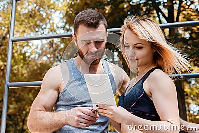 Young athletic girl and bearded man browsing the internet on tab Stock Photo