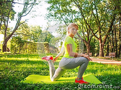 Young athletic girl doing fitness exercises in summer green park, training day for taking care of health in nature Stock Photo