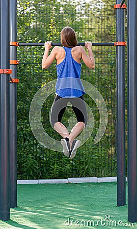 Young athletic girl pulls on the bar. Stock Photo