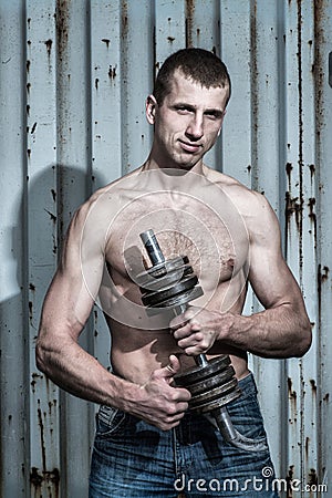 Young athletic man doing sport exercises with dumbbell Stock Photo