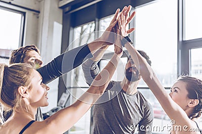 Young athletic people in sportswear giving high five in gym Stock Photo