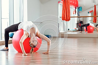 Young athletic woman doing exercises with fitness ball in gym Stock Photo