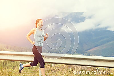 Young athletic woman jogging on road in mountains Stock Photo