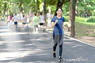 Young attractive asian runner woman running in urban public nature park in city Stock Photo