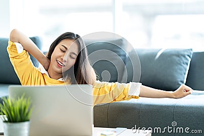 Young attractive asian woman work at home wearing casual yellow shirt in living room Stock Photo