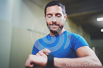 Young attractive athlete tracking burned calories on electronic smart watch application after good indoor workout Stock Photo