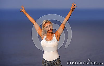 Young attractive and beautiful 30s blond hair woman in casual top and denim shorts spreading arms happy and cheerful posing Stock Photo