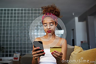 Young attractive black african female holding hands credit card and mobile phone hands. Technology, internet banking, e Stock Photo